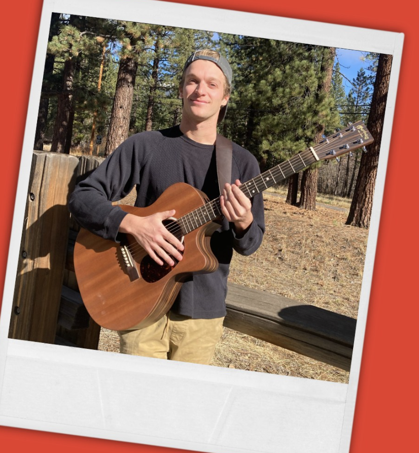 A young man holding an acoustic guitar